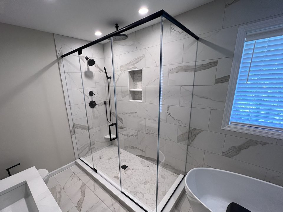 The same corner after: a glass corner enclosure with a slim matte black header and pull next to the freestanding tub