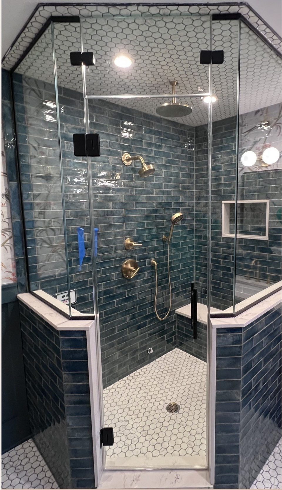 The same corner after: a neo-angle frameless glass enclosure sitting on the knee walls with matte black clips and pull