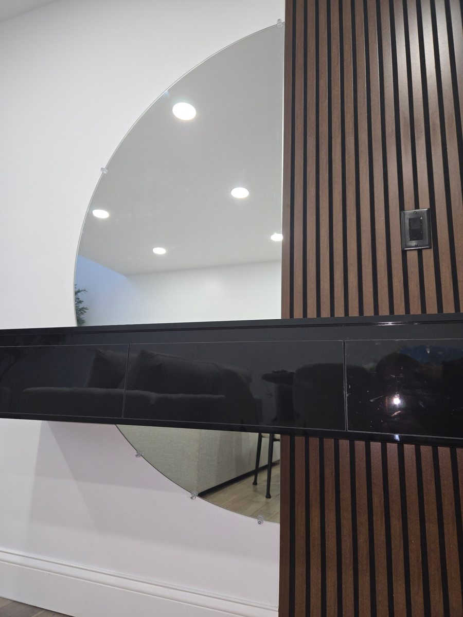 Black back-painted glass feature wall with a round mirror