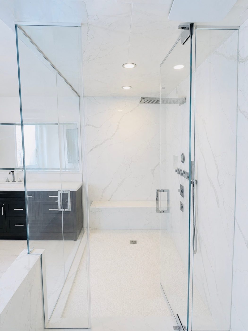 Frameless door and panel in a slab marble shower with a bench