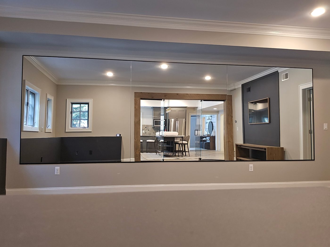 Large black-framed wall mirror reflecting an open kitchen