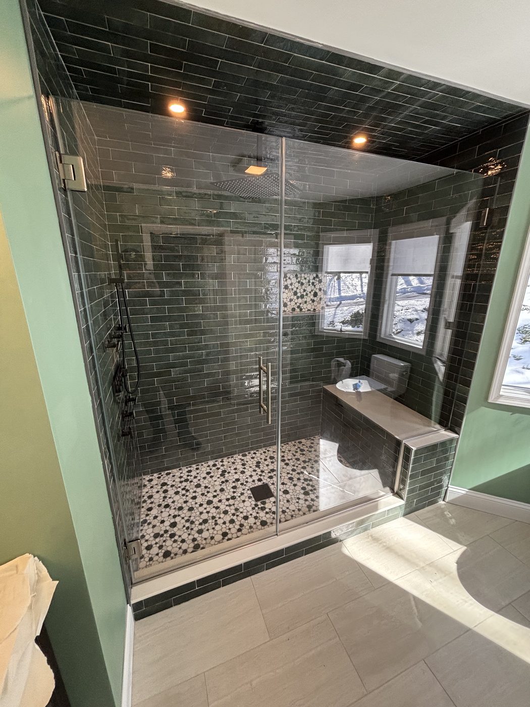 Frameless glass shower with dark mosaic tile and chrome hardware