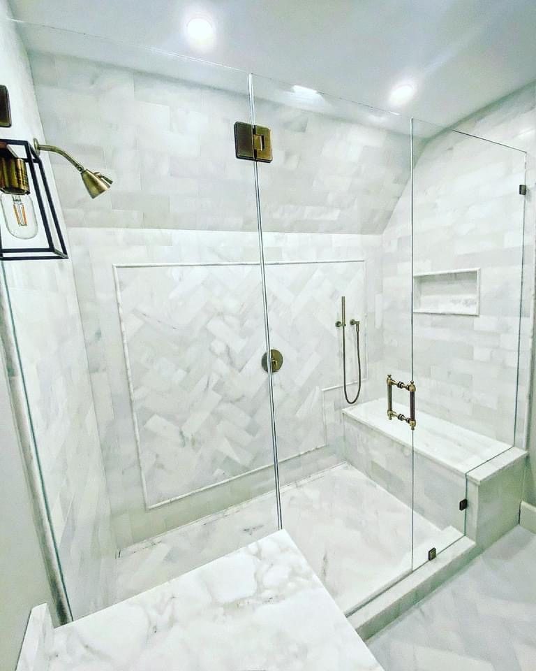 Frameless corner shower enclosure with marble tile and gold hardware