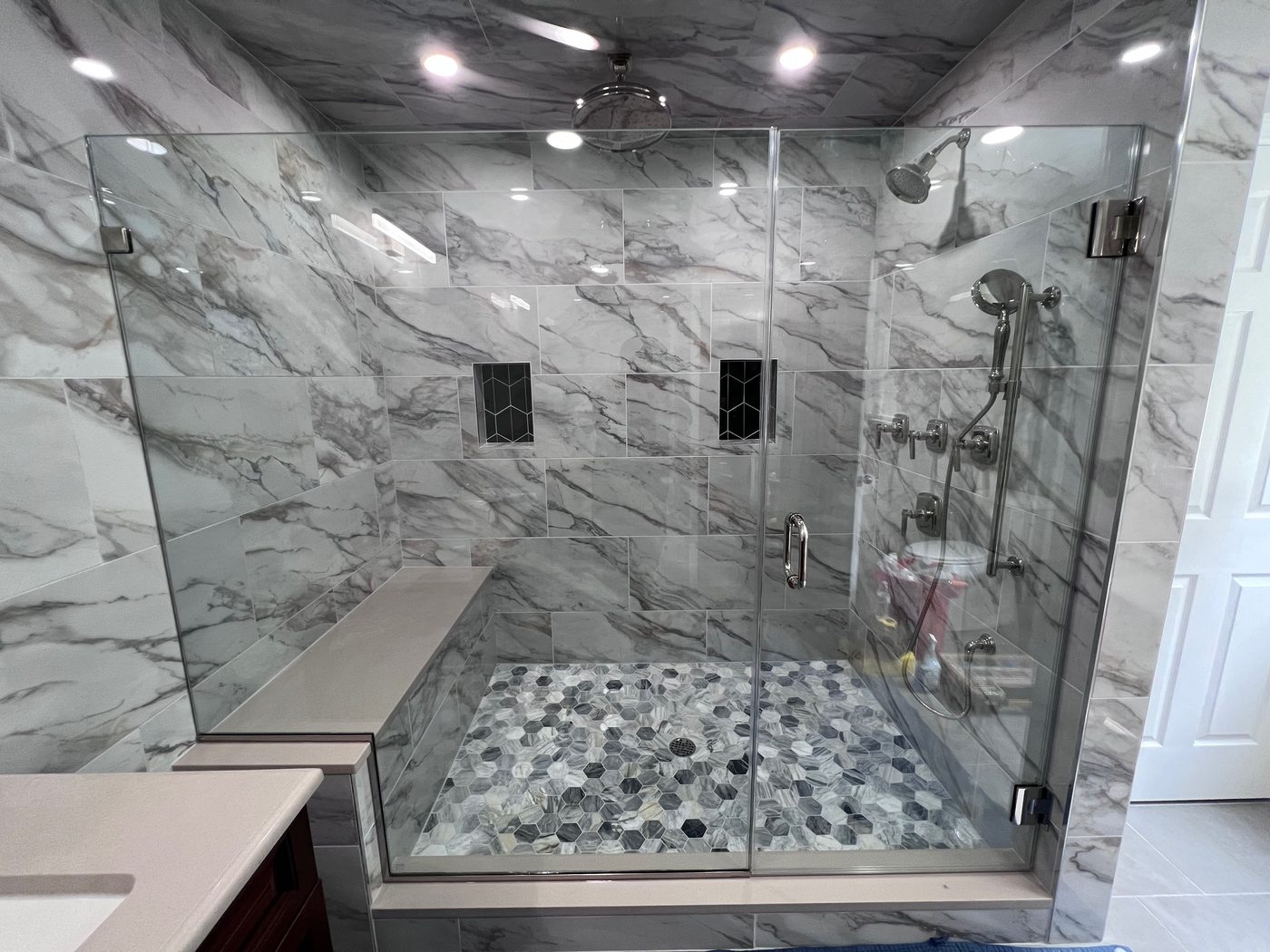Frameless shower with white marble walls and pebble-stone floor