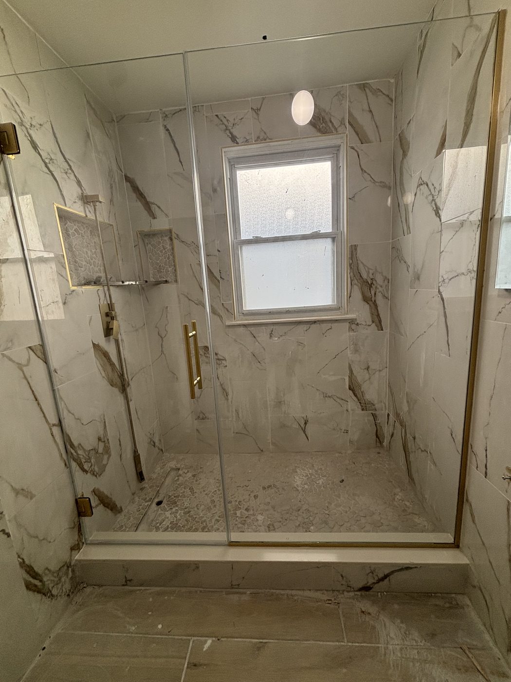 Frameless shower with Calacatta marble walls and gold trim