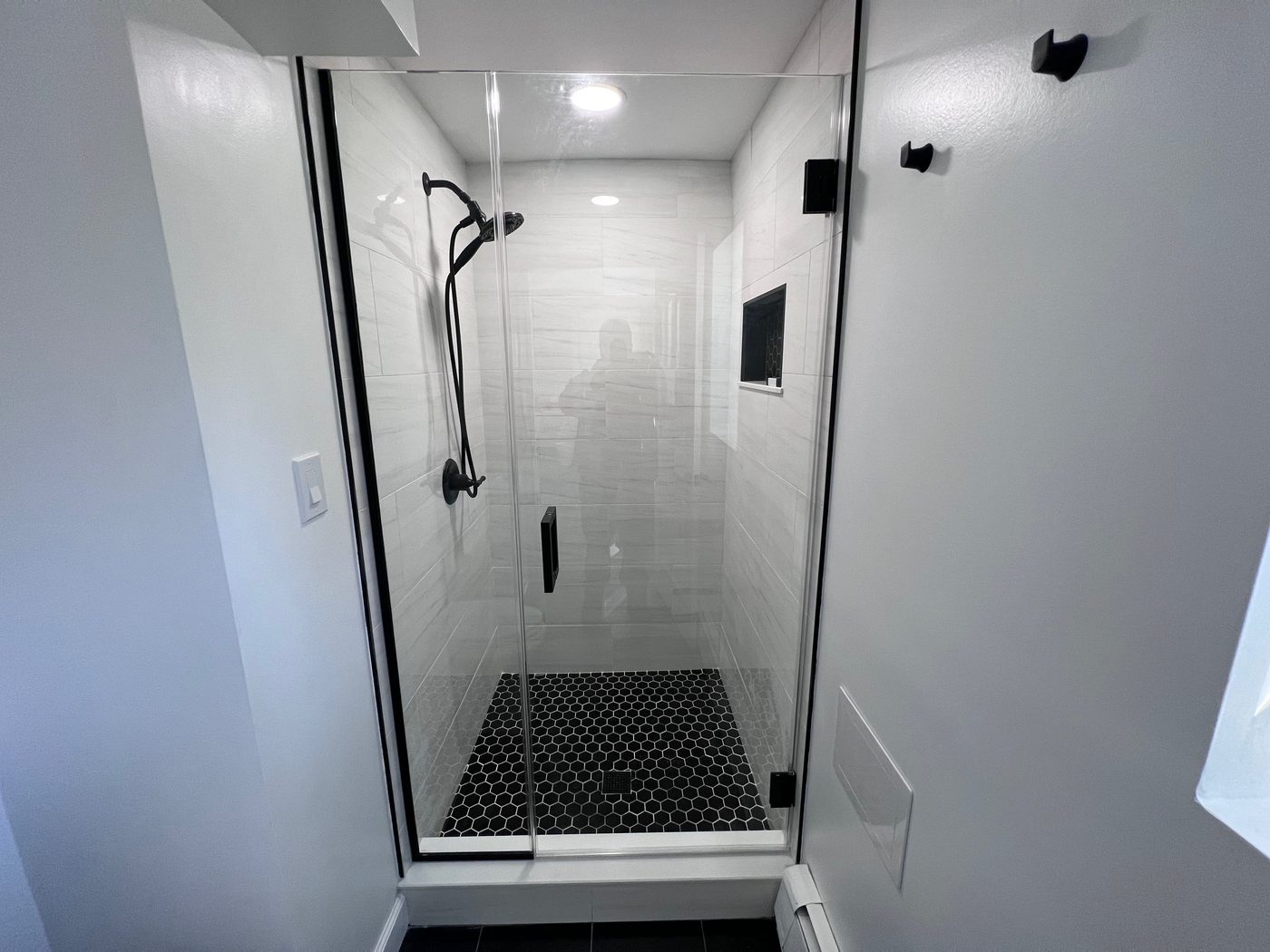 Frameless corner shower with white subway tile and matte-black hardware