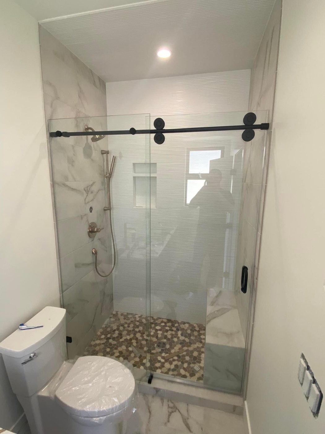 Frameless glass shower with black barn-door sliding hardware