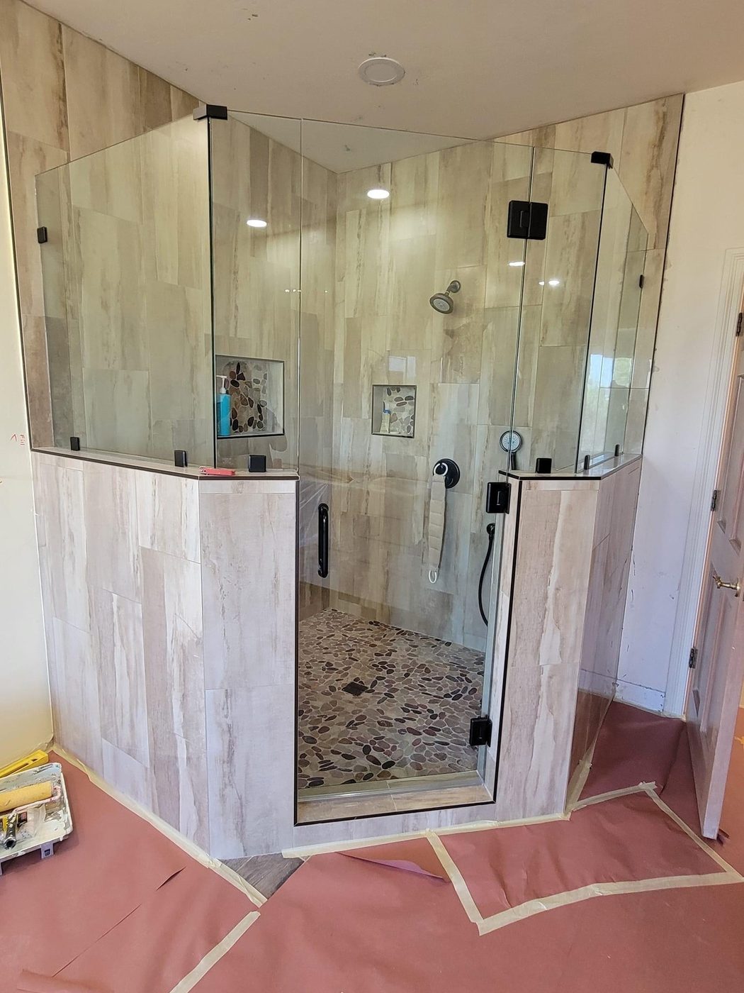 Frameless glass shower enclosure with marble walls and gold hardware