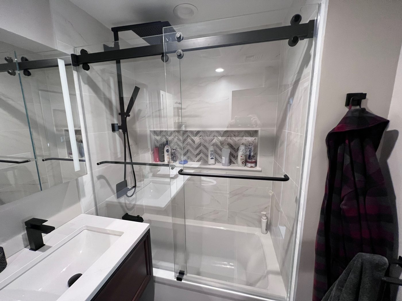 Sliding glass shower door beside a modern vanity