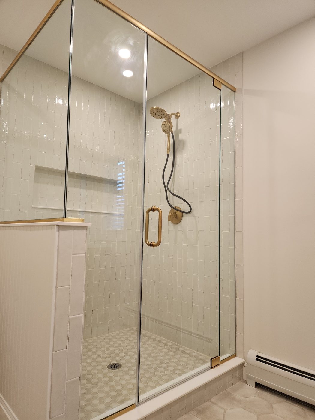 Frameless corner shower with gold hardware and marble