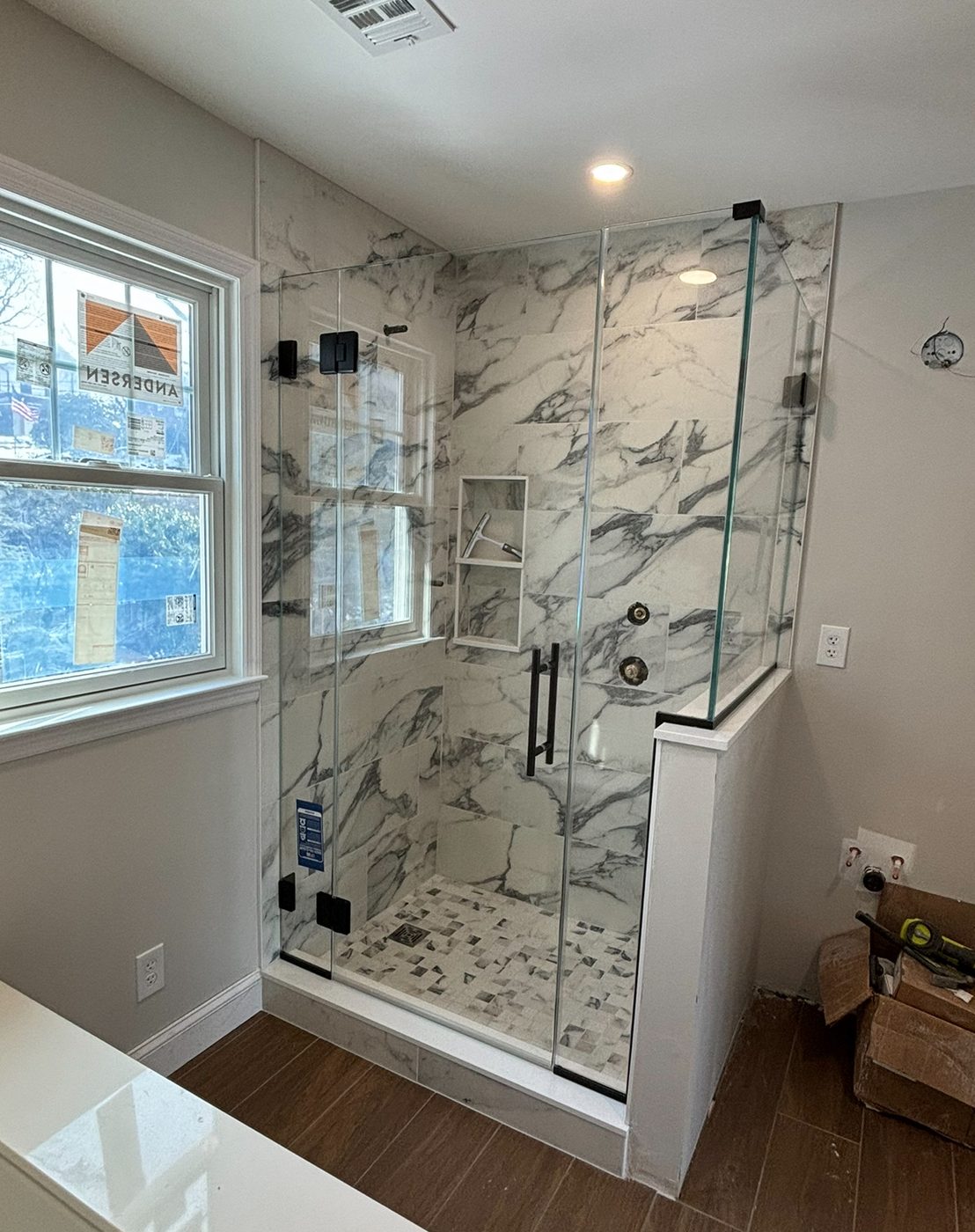 Frameless glass shower with marble walls and bench