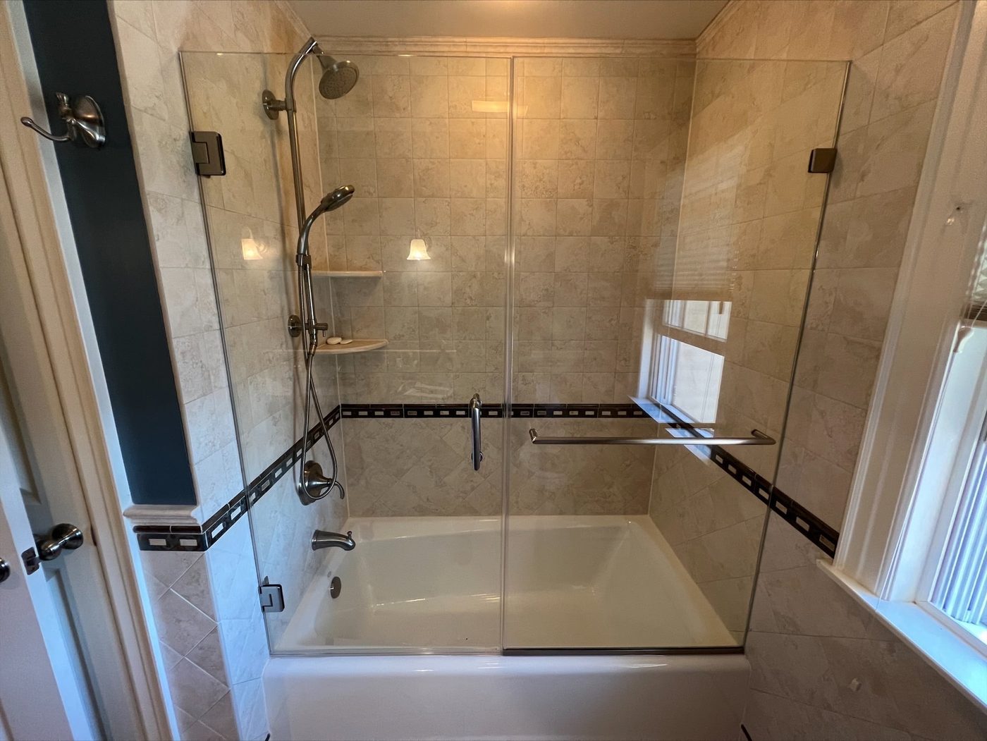Frameless glass tub enclosure over a white bathtub